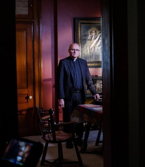Father Lampert standing in office