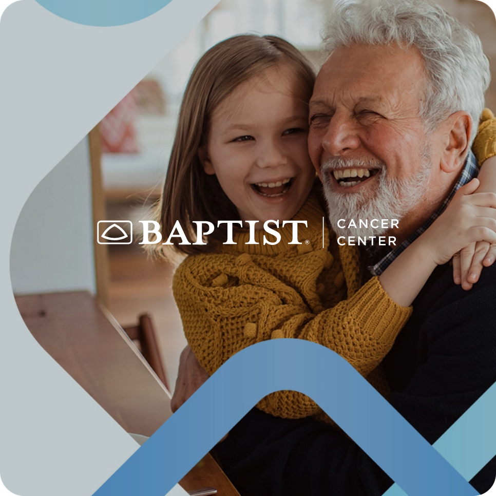 Smiling grandfather hugging young girl, who is wearing a yellow sweater, with Baptist Cancer Center logo overlay